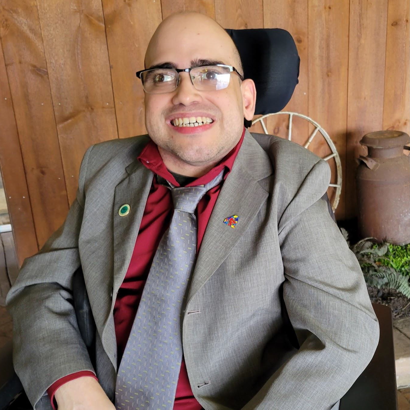 KN-Bio Smiling bald caucasian man in black glasses and grey suit with red shirt sitting in wheelchair