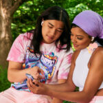 Two people sitting in a park reviewing info on a mobile phone